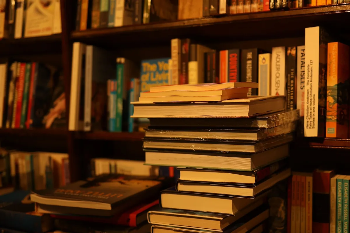 Stack of books on a table in front of full bookshelves