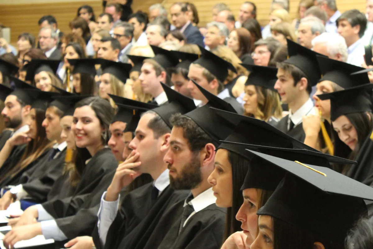 Graduates in caps and gowns seated in an auditorium during a graduation ceremony